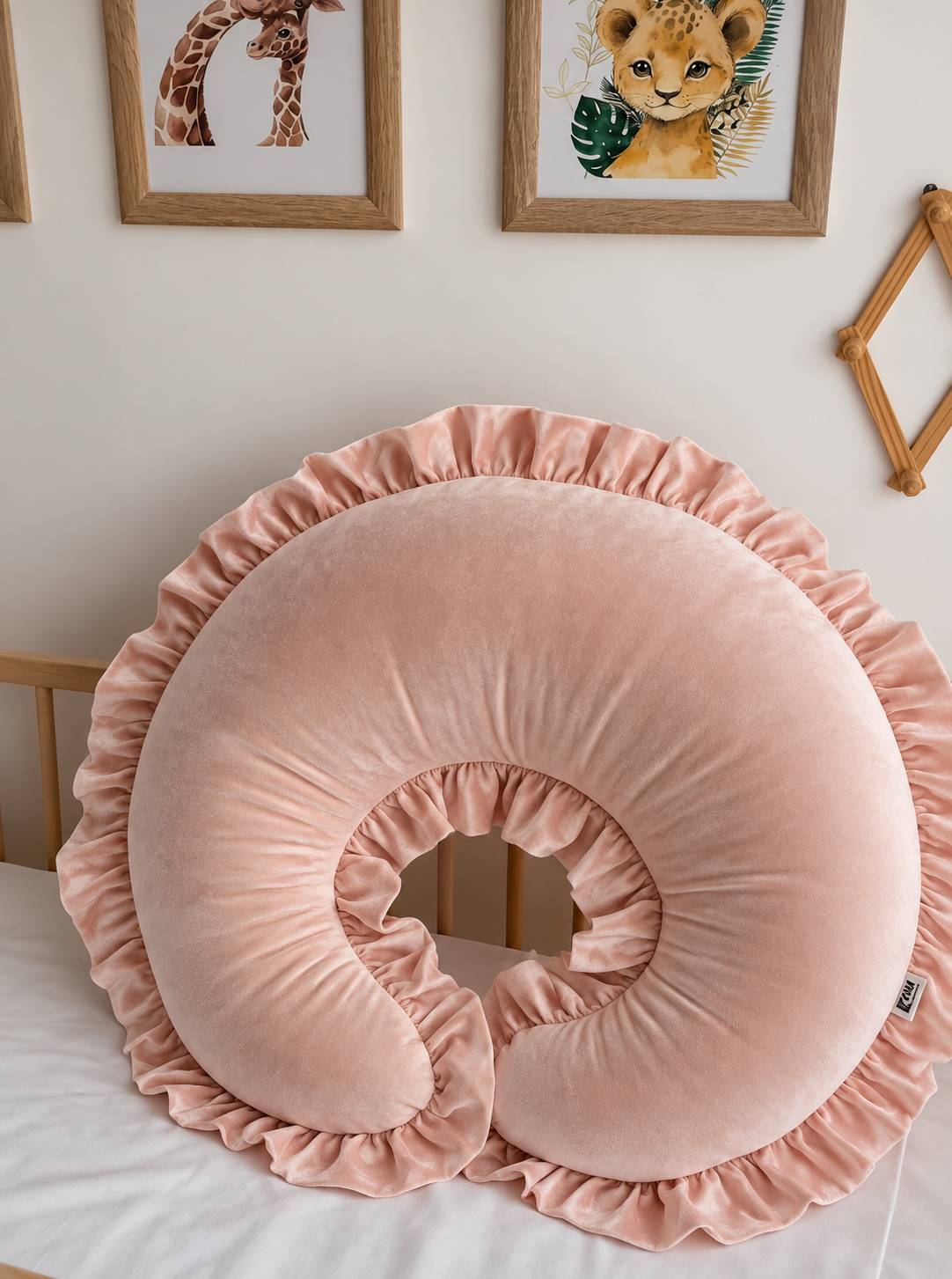 Blush-pink velvet nursing pillow with gathered ruffle trim