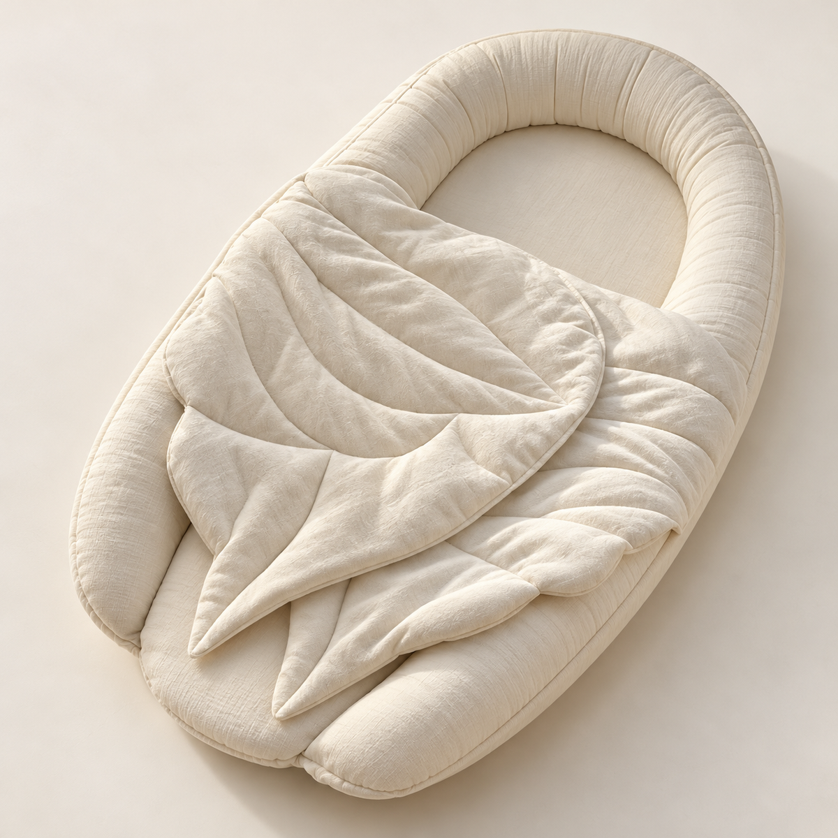 KNOTZ ivory oval baby nest with rounded padded sides and a quilted leaf-shaped detail, shown from above
