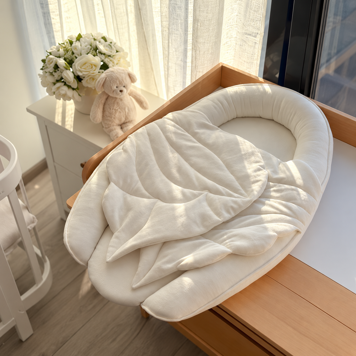 KNOTZ ivory oval baby nest with quilted leaf-shaped front detail in a neutral nursery